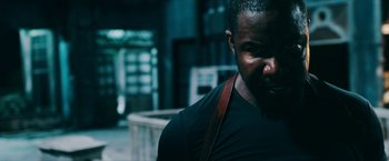 Movie still from “Triple Threat” (2019), directed by Jesse V. Johnson – A person wearing a black shirt; Close Up shot, Low angle