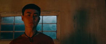 Movie still from “Triple Threat” (2019), directed by Jesse V. Johnson – A man standing in front of a window in a room; Close Up shot, Low angle