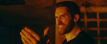 Movie still from “Triple Threat” (2019), directed by Jesse V. Johnson – A person with a beard; Close Up shot, Over the shoulder angle