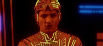 Movie still from “Tron” (1982), directed by Steven Lisberger – A man in a red and yellow costume with a helmet on his head; Close Up shot, Low angle