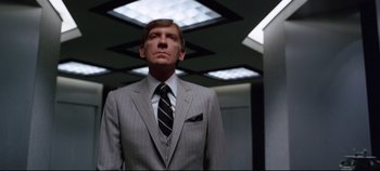 Movie still from “Tron” (1982), directed by Steven Lisberger – A man in a suit and tie standing in a room; Medium shot, Low angle