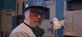 Movie still from “Tron” (1982), directed by Steven Lisberger – An older man wearing a hard hat and glasses; Close Up shot, Low angle