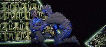 Movie still from “Tron” (1982), directed by Steven Lisberger – A man sitting on the ground next to another man; Medium shot, Low angle