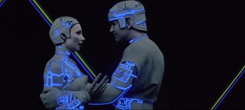 Movie still from “Tron” (1982), directed by Steven Lisberger – A couple of people that are standing up in the dark; Close Up shot, Overhead angle