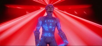 Movie still from “Tron” (1982), directed by Steven Lisberger – A man in a suit and helmet standing in front of a red background; Medium shot, Low angle