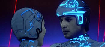 Movie still from “Tron” (1982), directed by Steven Lisberger – A man and a robot face to face in front of a blue background; Close Up shot, Over the shoulder angle