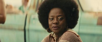 An older woman with a large afro is posing for a picture