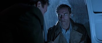 Movie still from “True Lies” (1994), directed by James Cameron – A man looking at another man in the rain; Close Up shot, Over the shoulder angle