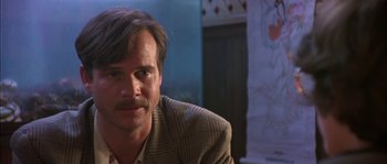 Movie still from “True Lies” (1994), directed by James Cameron – A person wearing a suit and tie; Close Up shot, Over the shoulder angle