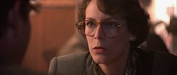 Movie still from “True Lies” (1994), directed by James Cameron – A person wearing glasses and a suit; Close Up shot, Over the shoulder angle