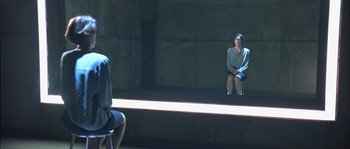 Movie still from “True Lies” (1994), directed by James Cameron – A woman sitting on a chair in front of a man; Wide shot, Over the shoulder angle