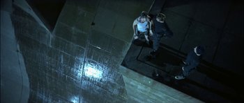 Movie still from “True Lies” (1994), directed by James Cameron – Two people standing on a ledge in the dark; Wide shot, Overhead angle