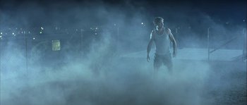 Movie still from “True Lies” (1994), directed by James Cameron – A man standing in the middle of a foggy street at night; Wide shot, Low angle