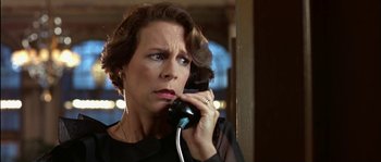 Movie still from “True Lies” (1994), directed by James Cameron – A woman talking on a phone while standing in front of a window; Close Up shot, Low angle