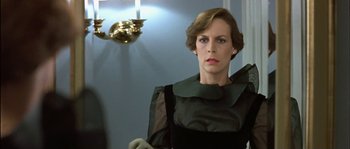 Movie still from “True Lies” (1994), directed by James Cameron – A woman in a black dress standing in front of a mirror; Close Up shot, Low angle