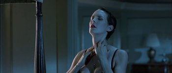 Movie still from “True Lies” (1994), directed by James Cameron – A woman with short black hair is holding her neck; Close Up shot, Low angle