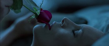 Movie still from “True Lies” (1994), directed by James Cameron – A woman with her eyes closed is smelling a rose; Extreme Close Up shot, Overhead angle