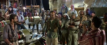 Movie still from “True Lies” (1994), directed by James Cameron – A group of men standing next to each other on a dock; Wide shot, Over the shoulder angle