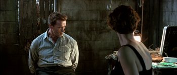 Movie still from “True Lies” (1994), directed by James Cameron – A man and a woman are sitting in front of a brick wall; Medium shot, Over the shoulder angle