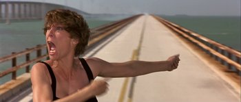 Movie still from “True Lies” (1994), directed by James Cameron – A man running across a bridge with his arms outstretched; Medium shot, High angle