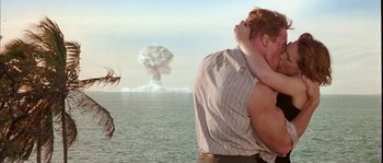 Movie still from “True Lies” (1994), directed by James Cameron – A man and a woman hug in front of a nuclear explosion; Medium shot, Low angle