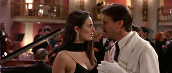 Movie still from “True Lies” (1994), directed by James Cameron – A man and a woman in a black dress and white gloves; Close Up shot, Over the shoulder angle