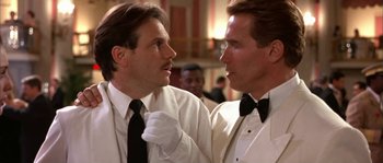 Movie still from “True Lies” (1994), directed by James Cameron – A couple of men standing next to each other; Close Up shot, Low angle