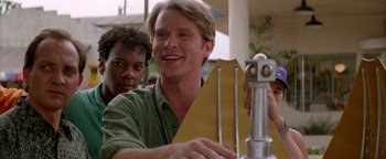 Movie still from “Twister” (1996), directed by Jan de Bont – A man smiles while holding an object in front of him; Close Up shot, Low angle