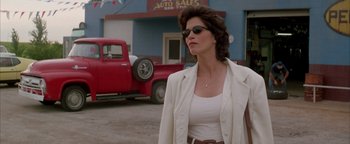 Movie still from “Twister” (1996), directed by Jan de Bont – A woman wearing sunglasses and a white jacket walking down a street; Medium shot, Low angle
