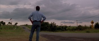 Movie still from “Twister” (1996), directed by Jan de Bont – A man standing on the side of a road looking out at a cloudy sky; Extreme Wide shot, Low angle