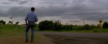 Movie still from “Twister” (1996), directed by Jan de Bont – A man standing on the side of a road looking out at the sky; Wide shot, Low angle