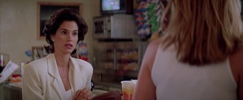 Movie still from “Twister” (1996), directed by Jan de Bont – Two women sitting at a table in front of a tv; Close Up shot, Over the shoulder angle