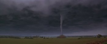 Movie still from “Twister” (1996), directed by Jan de Bont – A tornado is seen in the distance in a field; Extreme Wide shot, High angle