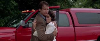 Movie still from “Twister” (1996), directed by Jan de Bont – A man and a woman hugging in front of a red truck; Medium shot, Low angle