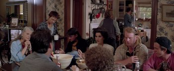 Movie still from “Twister” (1996), directed by Jan de Bont – A group of people sitting at a table with food; Medium shot, Over the shoulder angle
