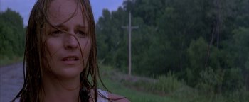 Movie still from “Twister” (1996), directed by Jan de Bont – A woman standing in front of a cross in a wooded area; Close Up shot, Low angle
