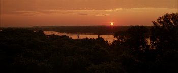 Movie still from “Twister” (1996), directed by Jan de Bont – The sun is setting over a body of water; Extreme Wide shot, High angle