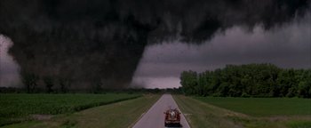 Movie still from “Twister” (1996), directed by Jan de Bont – A truck driving down a road with a large tornado in the background; Extreme Wide shot, High angle