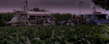 Movie still from “Twister” (1996), directed by Jan de Bont – A group of people standing in front of a bus in a corn field; Extreme Wide shot, Low angle