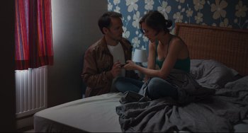 Movie still from “Two Days, One Night” (2014), directed by Jean-Pierre Dardenne – A man and a woman sitting on a bed together; Medium shot, High angle