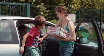Movie still from “Two Days, One Night” (2014), directed by Jean-Pierre Dardenne – A woman and a boy are holding boxes of pizza; Medium shot, Over the shoulder angle