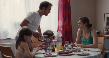 Movie still from “Two Days, One Night” (2014), directed by Jean-Pierre Dardenne – A group of people sitting at a table with plates of food on it; Medium shot, High angle