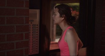 Movie still from “Two Days, One Night” (2014), directed by Jean-Pierre Dardenne – A woman in a pink shirt is standing in front of a phone booth; Medium shot, Over the shoulder angle