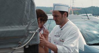 Movie still from “Two Days, One Night” (2014), directed by Jean-Pierre Dardenne – A man and a woman wearing chef's hats; Medium shot, Over the shoulder angle
