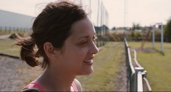 Movie still from “Two Days, One Night” (2014), directed by Jean-Pierre Dardenne – A person outside near a fence; Close Up shot, Over the shoulder angle