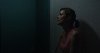 Movie still from “Two Days, One Night” (2014), directed by Jean-Pierre Dardenne – A woman in a pink tank top looking out of a window; Medium shot, Low angle