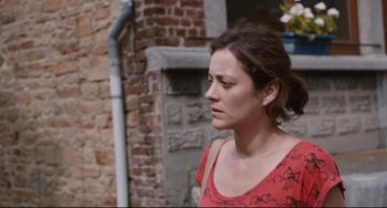 Movie still from “Two Days, One Night” (2014), directed by Jean-Pierre Dardenne – A person wearing a red shirt near a brick wall; Close Up shot, Over the shoulder angle