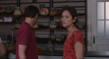 Movie still from “Two Days, One Night” (2014), directed by Jean-Pierre Dardenne – A man and a woman standing in front of a display of bread; Medium shot, Over the shoulder angle