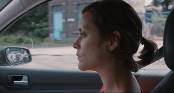 Movie still from “Two Days, One Night” (2014), directed by Jean-Pierre Dardenne – A woman sitting in the passenger seat of a car looking out the window; Close Up shot, Over the shoulder angle