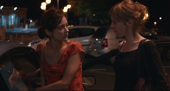 Movie still from “Two Days, One Night” (2014), directed by Jean-Pierre Dardenne – Two women standing next to each other on the street; Medium shot, Over the shoulder angle